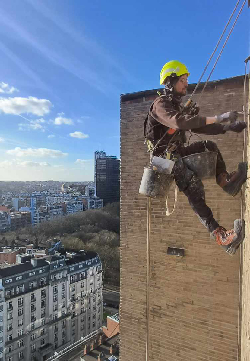 Réparation de béton et purge de sécurité sur une façade vitrée d'un immeuble de grande hauteur surplombant Namur.